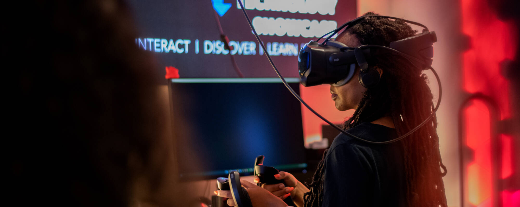 Person wearing a VR headset uses controls in an interactive exhibit.